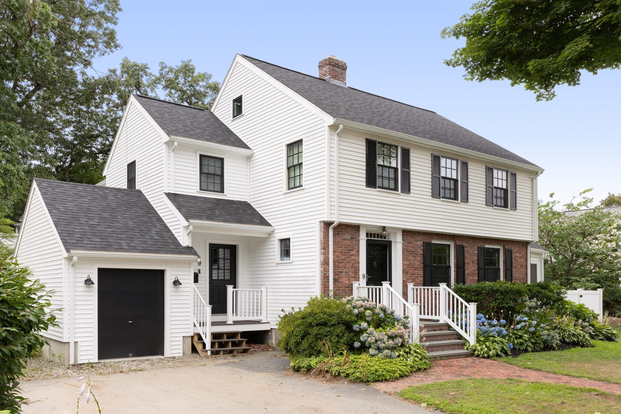 Home addition and exterior remodel of a colonial-style house in Boston, featuring white siding, black shutters, and a new garage, designed by Lee Kimball. Home addition and exterior remodel of a colonial-style house in Boston, featuring white siding, black shutters, and a new garage, designed by Lee Kimball.