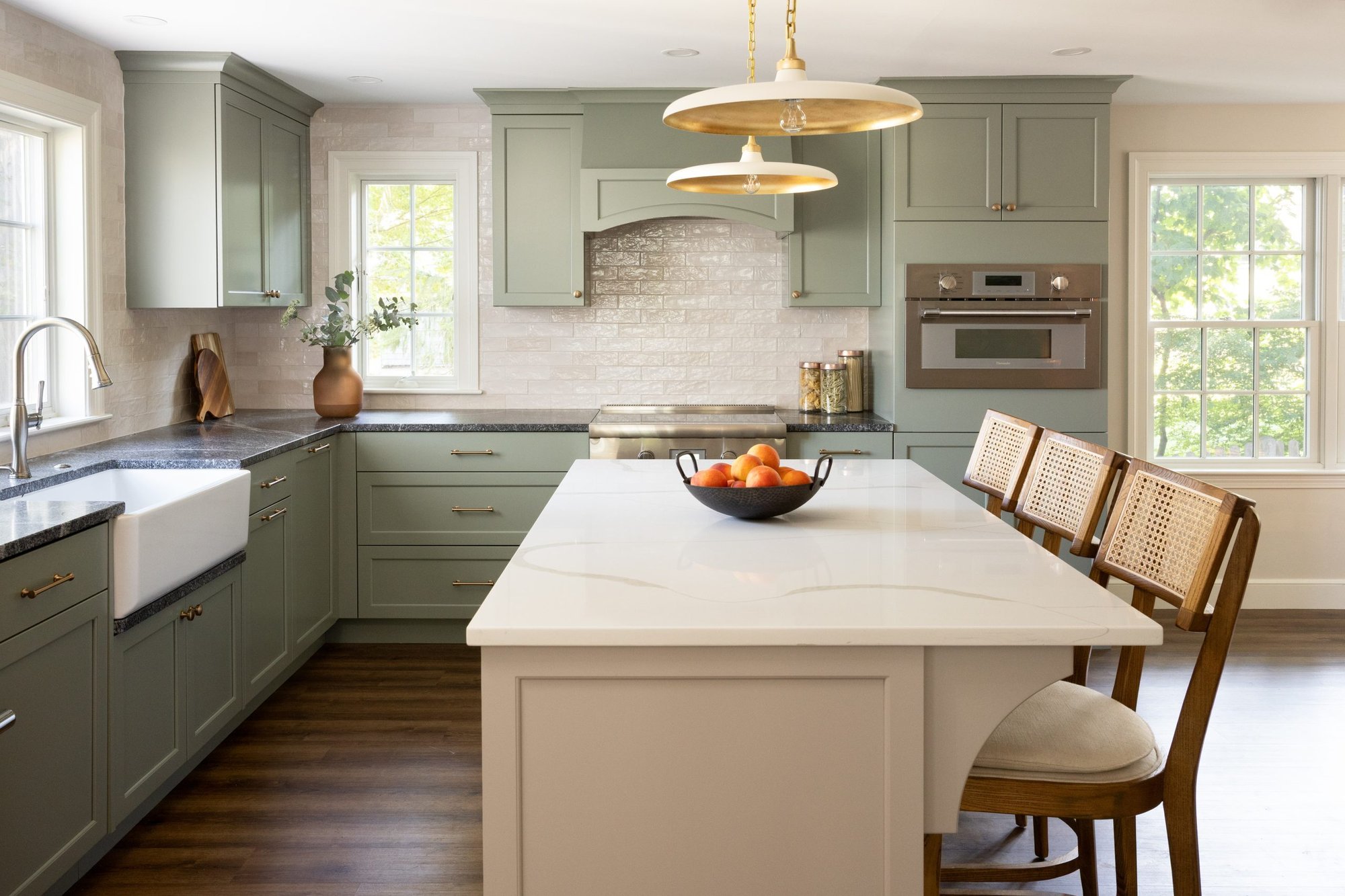 Kitchen remodel in Boston with sage green cabinetry, brass pendant lighting, and a large center island, designed by Lee Kimball. Kitchen remodel in Boston with sage green cabinetry, brass pendant lighting, and a large center island, designed by Lee Kimball.