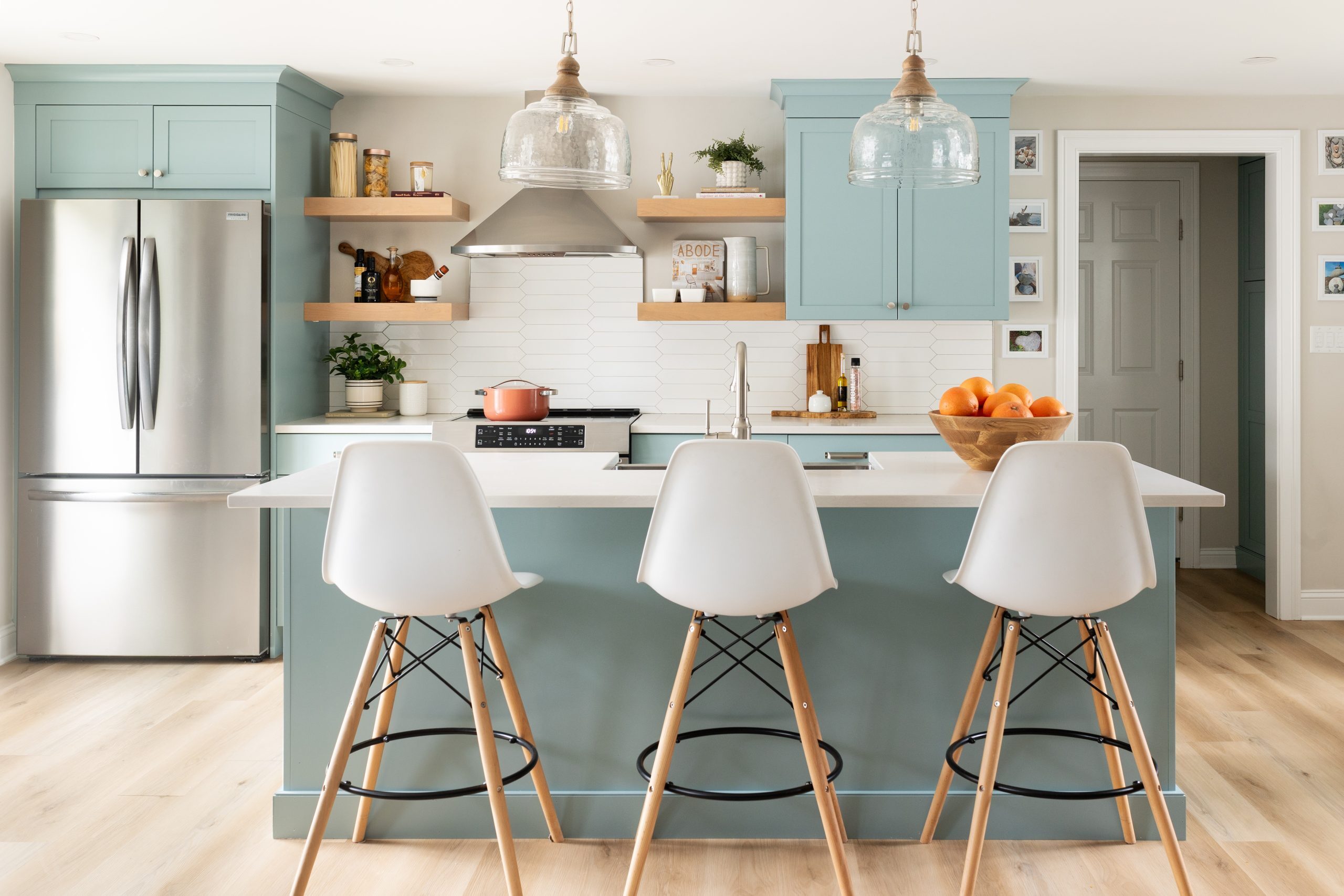 Contemporary kitchen with blue island and white bar stools in Greater Boston