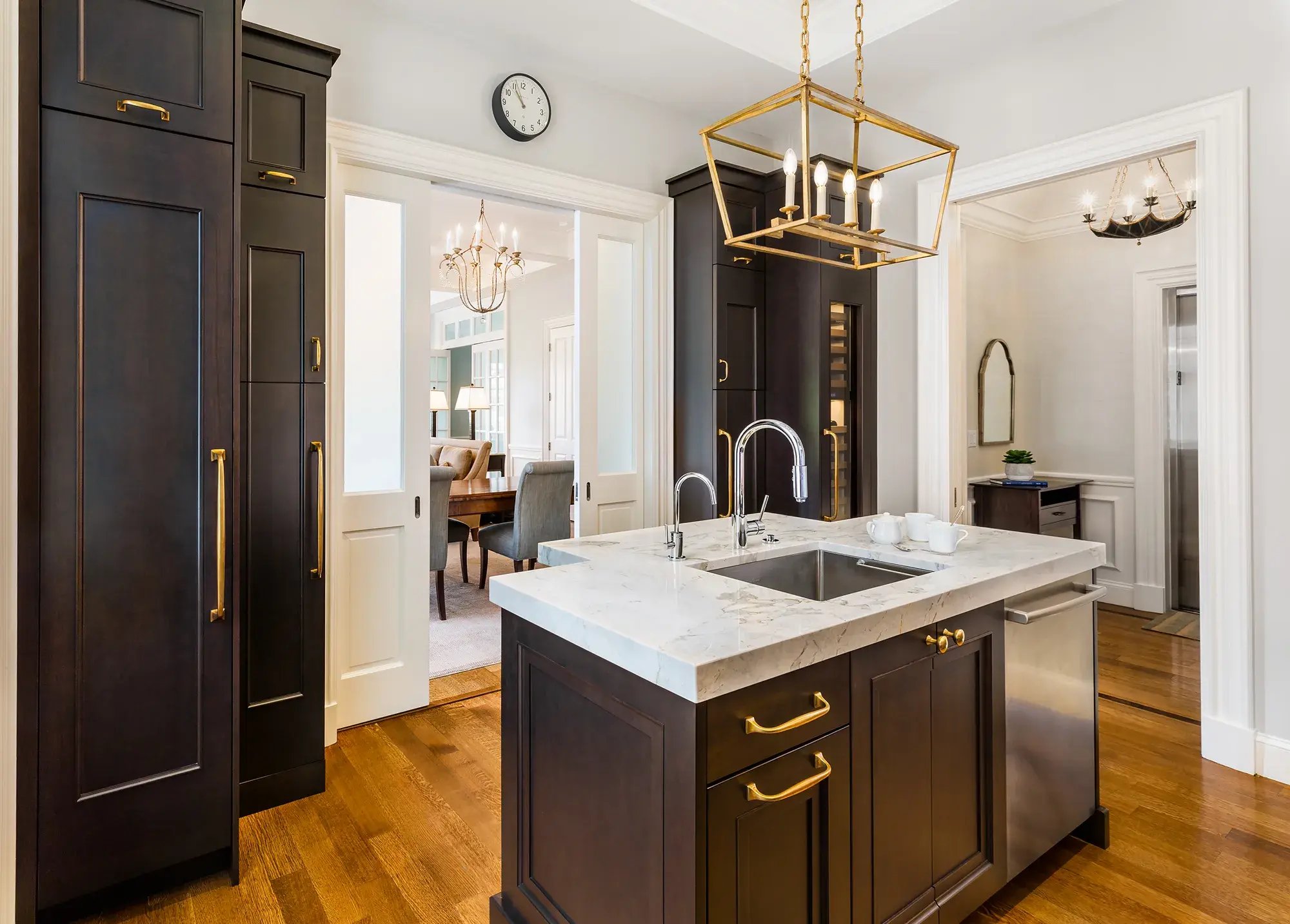 Dark wood kitchen with marble island and gold pendant lighting in Greater Boston