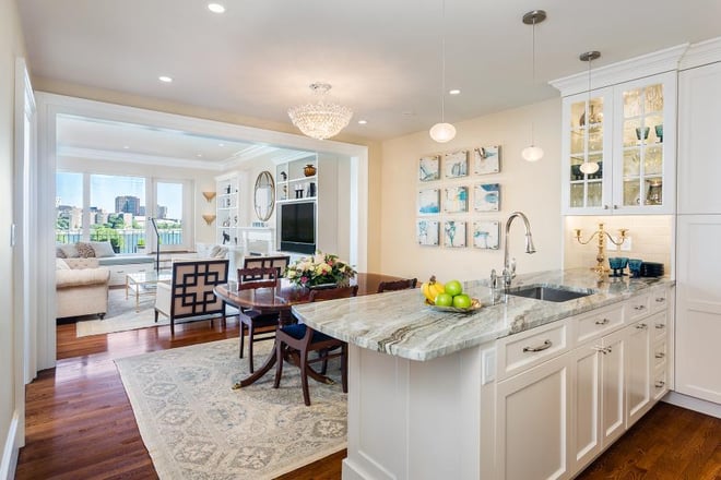 Open-concept kitchen and living area with marble island and hardwood floors in Greater Boston