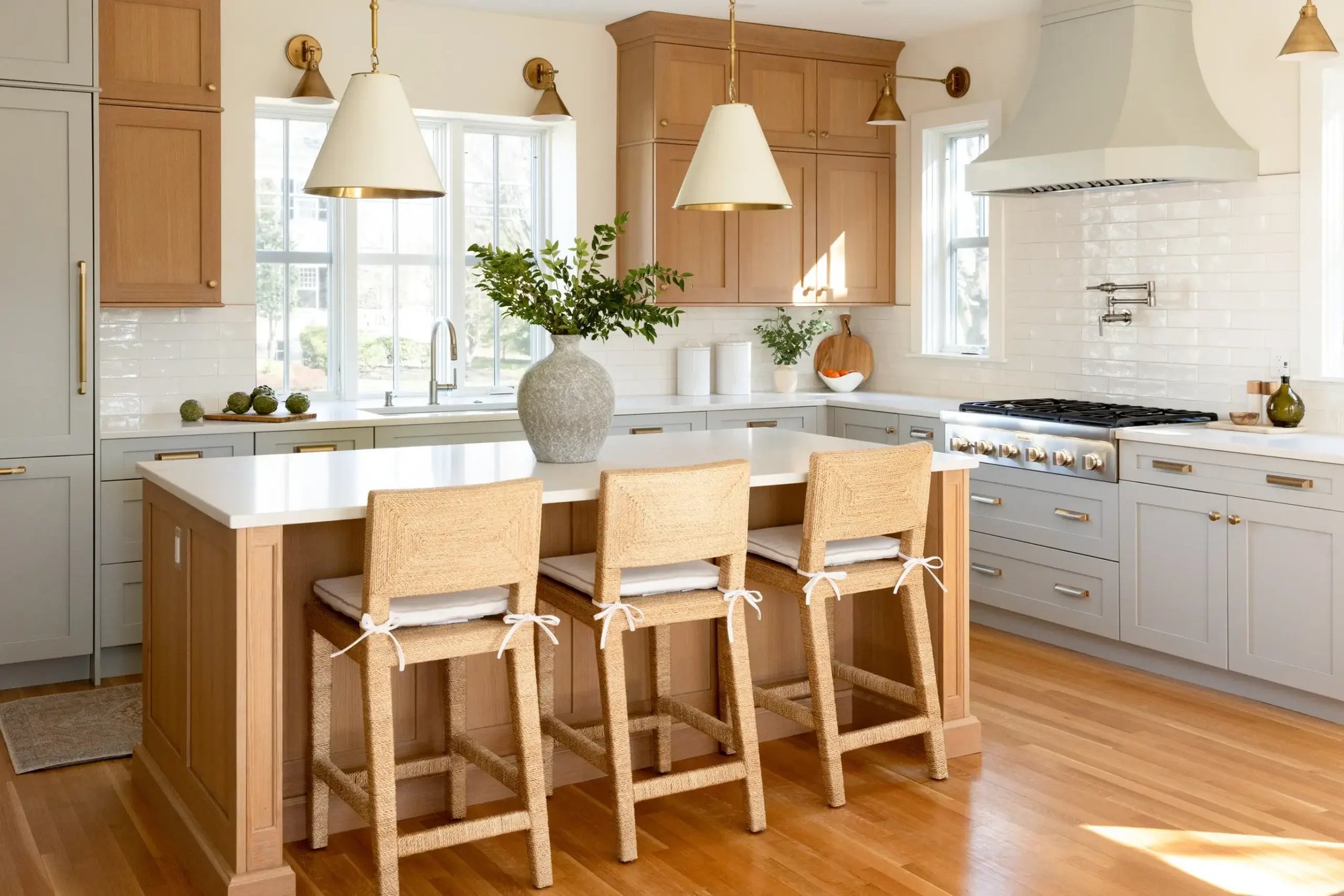 Sunlit kitchen with wood island seating and white cabinetry in Greater Boston