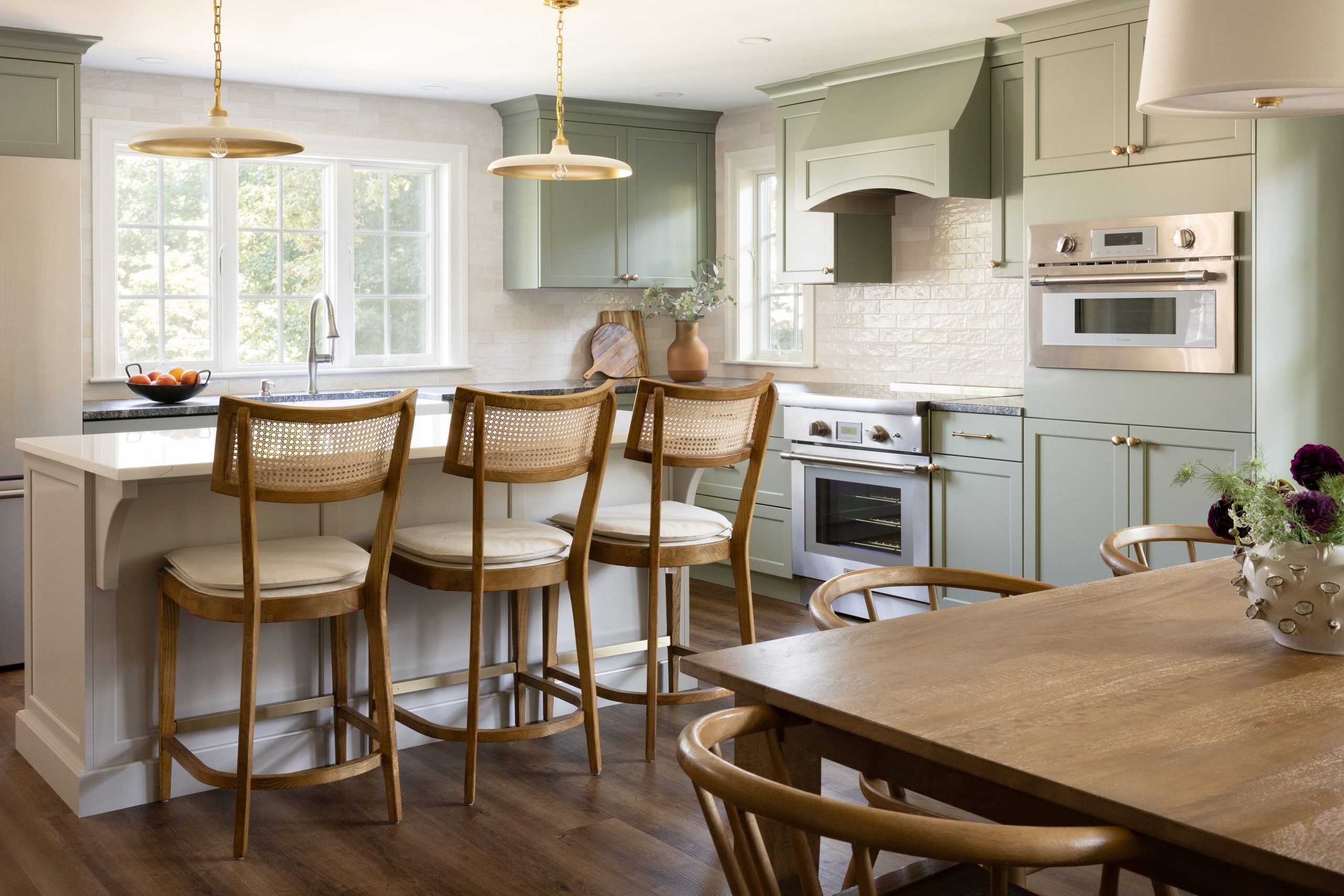 Warm kitchen with sage cabinets and island seating in Greater Boston
