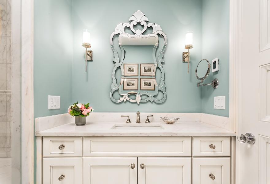 vanity in Boston bathroom remodel with light blue walls, stylish mirror and sconce lighting.