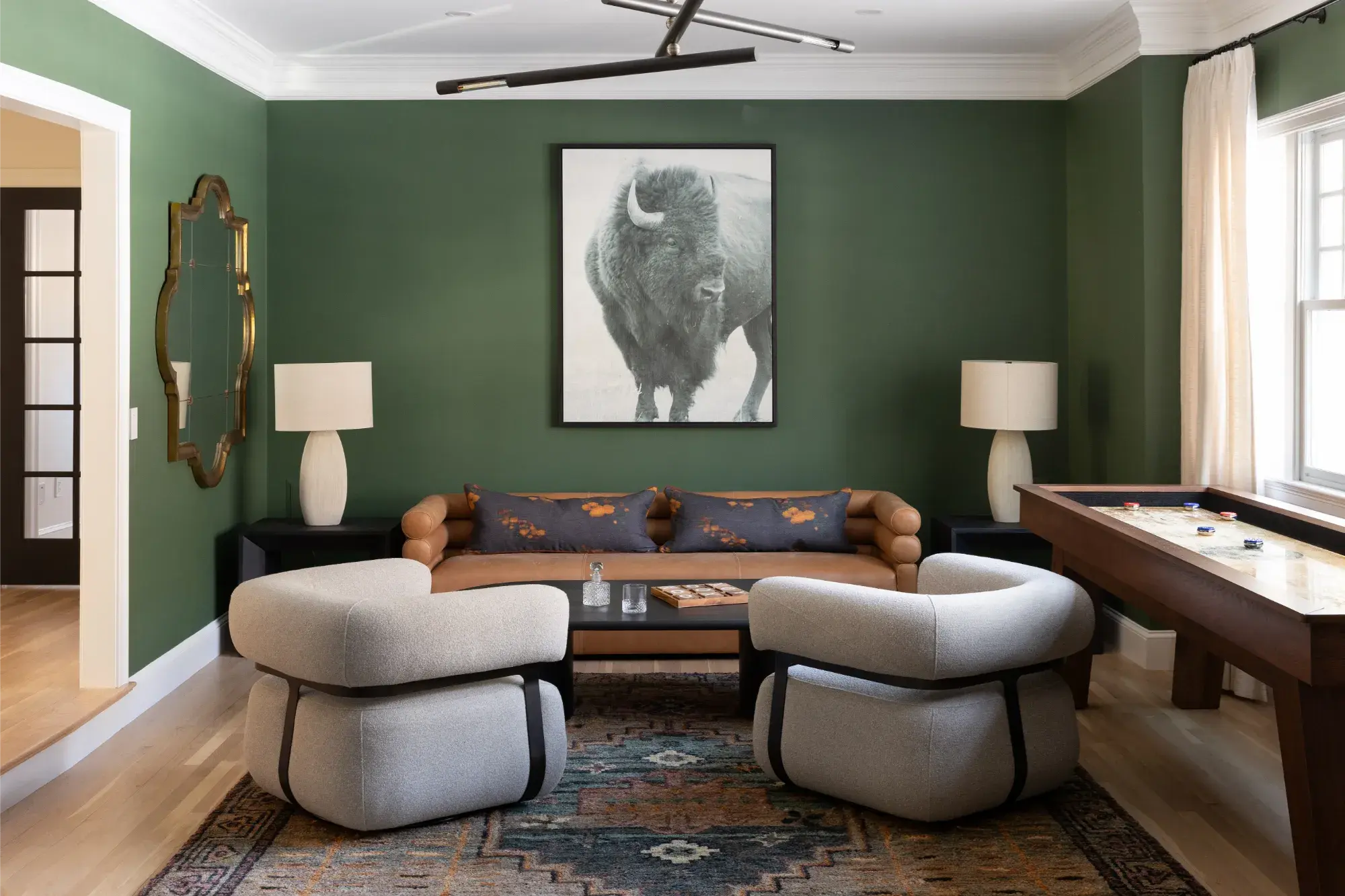 Stylish living room in Greater Boston with green walls, modern seating, and framed artwork centerpiece